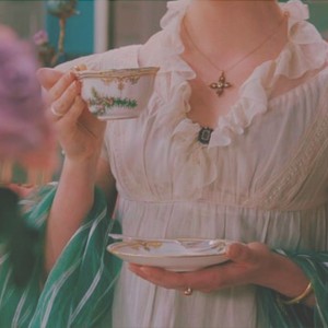 Woman in Regency-era gown drinking tea